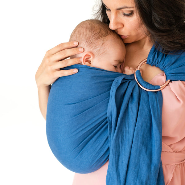 mom kissing baby's forehead in ring sling