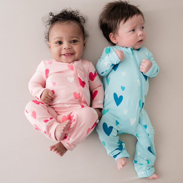 two babies wearing kyte baby rompers in crepe and robin hearts print