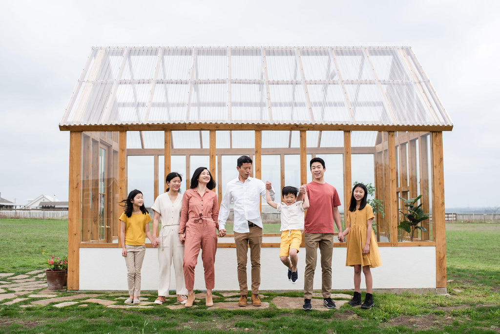 asian family of seven standing outside of a greenhouse holding hands
