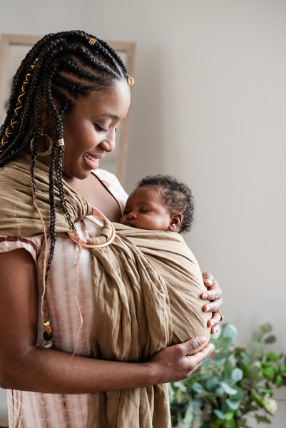 mom smiling down at baby in her ring sling