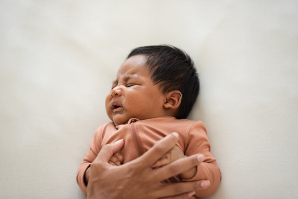 newborn baby fussing with mom's hand on chest