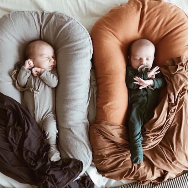 newborn twins sleeping side to side in loungers