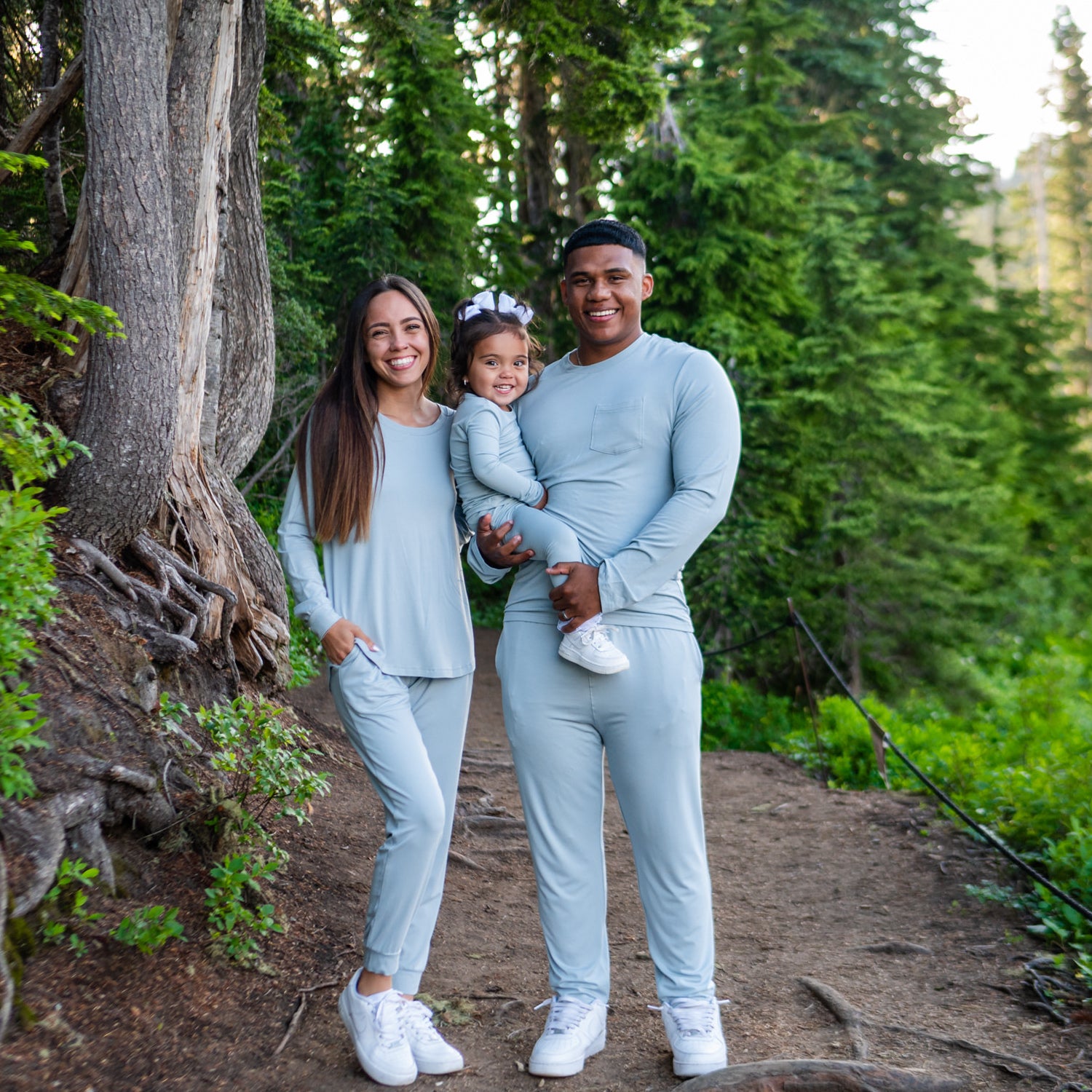 Mother and Father holding their child while standing in the woods wearing Kyte pajamas