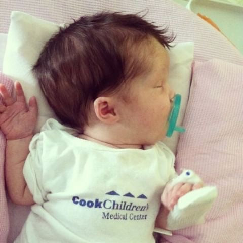 a new born baby named jolene, sleeping in a cook children's medical center bodysuit