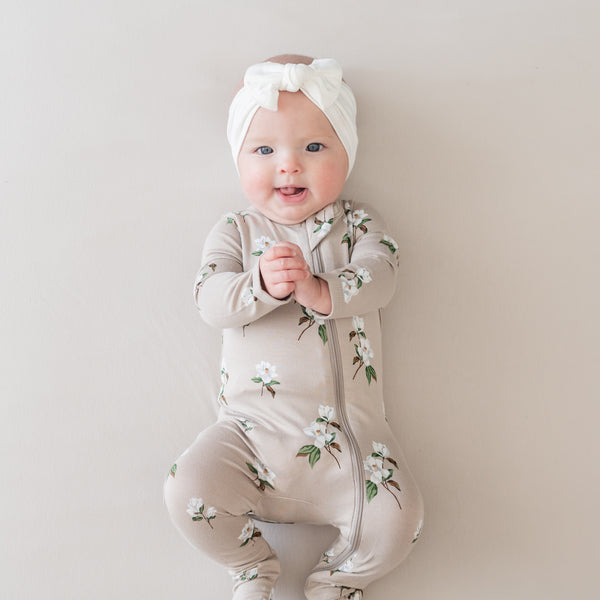 baby wearing kyte baby footie in magnolia print on khaki