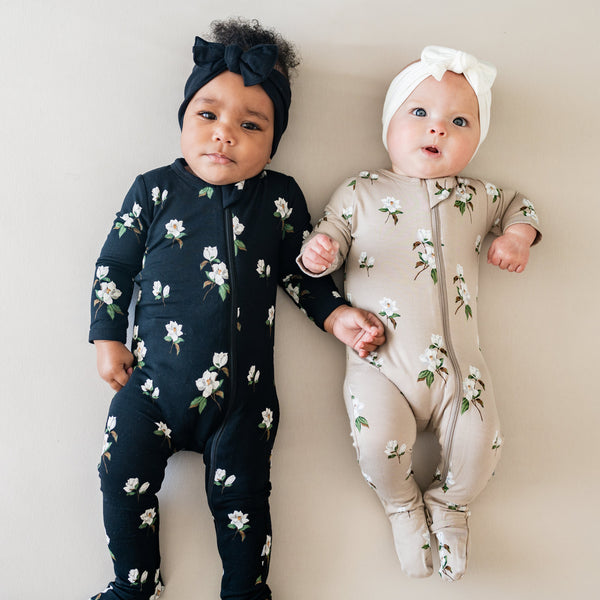 two babies wearing kyte baby magnolia print on midnight and khaki