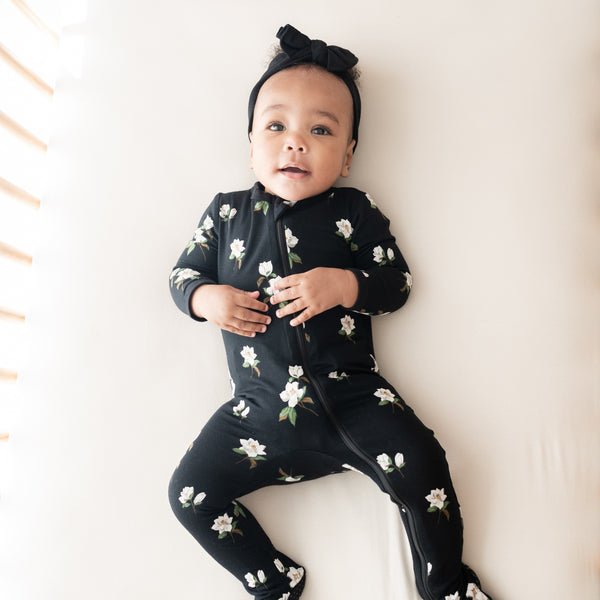 baby wearing kyte baby footie in magnolia print on midnight