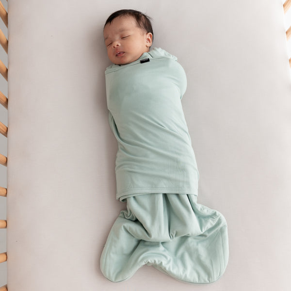 newborn baby wearing kyte baby sleep bag swaddler