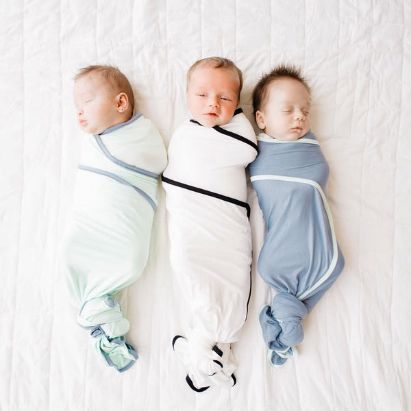 three newborn babies wrapped in swaddles laying next to each other