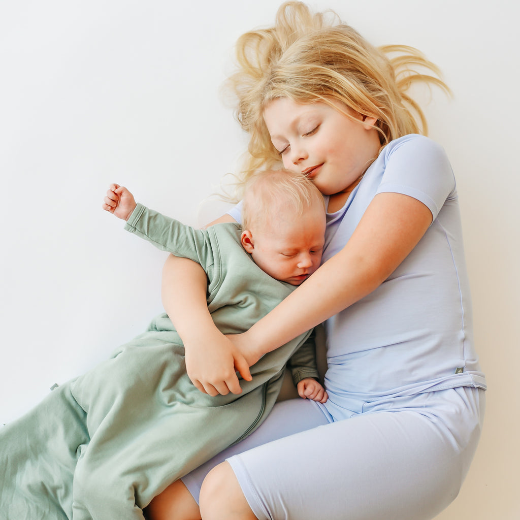 toddler and newborn sibling cuddling and sleeping in pajamas