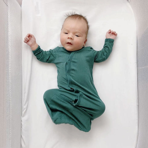 baby laying in bassinet and wearing a kyte baby bundler in emerald