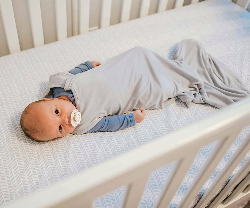 0.5 TOG Sleep Bag on Baby Laying in Crib and Staring off in Distance
