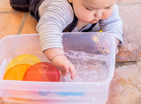 baby playing with a water sensory bin