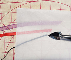 iron out wrinkles in ribbon by first placing an applique pressing sheet over the ribbon before putting iron or heat to it