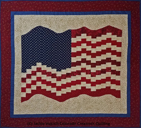 This quilt by Colorado Creations Quilting features a United States flag blowing in the breeze.