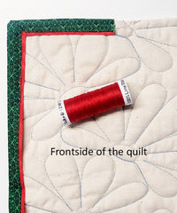 Front side of quilt showing a green binding and red flange with red thread.