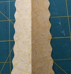 Image shows strip of fabric with both sides having a scalloped edge