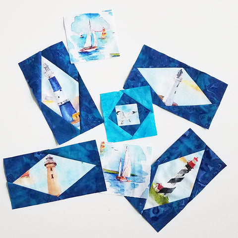 Cotton fabric featuring sailboats and lighthouses are fussy cut to become the center of quilt blocks.