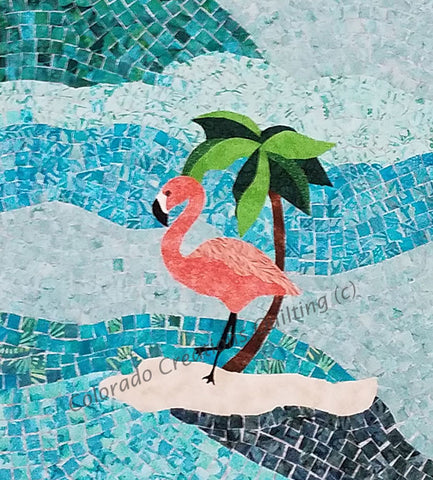 A quilt using the mosaic technique features a pink flamingo on a tiny sand island.  (c) Made by Jackie Vujcich of Colorado Creations Quilting