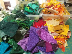 Brightly colored fabric in heaped in a messy pile.
