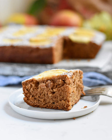 slice of applesauce cake on plate with full cake in background
