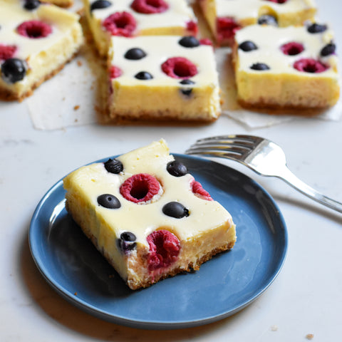 cheesecake bar slice studded with raspberries and blueberries on plate