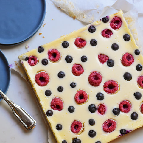 whole pan of cheesecake bar studded with raspberries and blueberries overhead