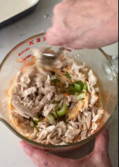 mixing celery and chicken with buffalo sauce