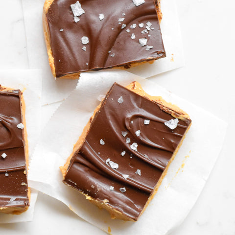 overhead view of three slices of chocolate peanut butter bars sprinkled with salt
