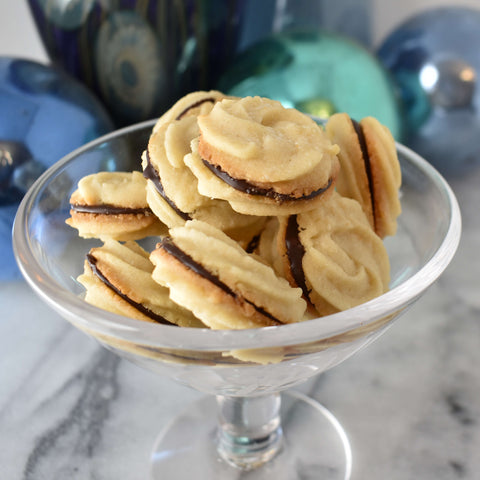 butter cookie sandwiches served in a martini glass with blue shiny balls in background