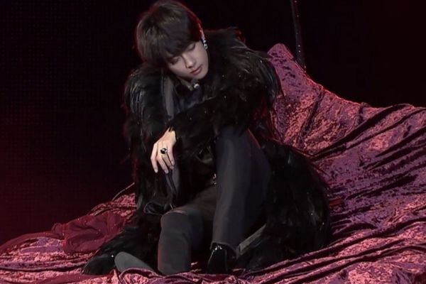 V sitting on a velvet covered bed during his Singularity performance during the BTS Love Yourself Speak Yourself The Final concerts. 