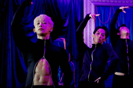 Wonho danse avec le bras droit élevé, deux danseurs supplémentaires dans la même pose