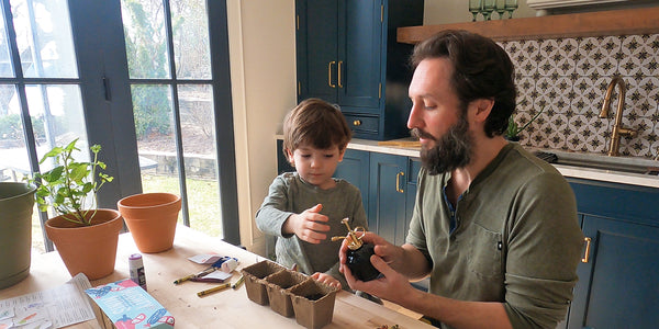 dad and toddler son planting at a kitchen table together