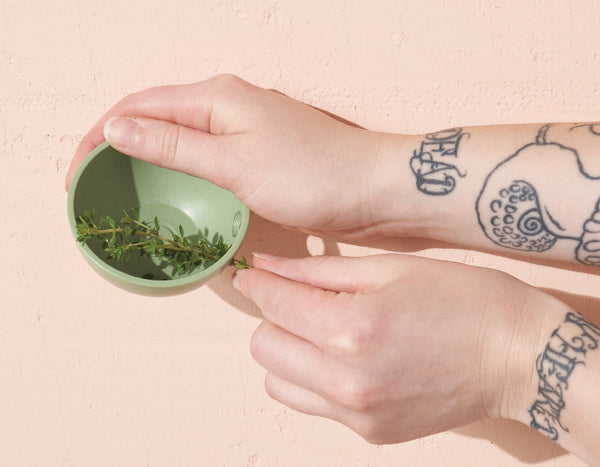 two hands demonstrating Modern Sprout's herb pull & pinch dish with a rosemary sprig