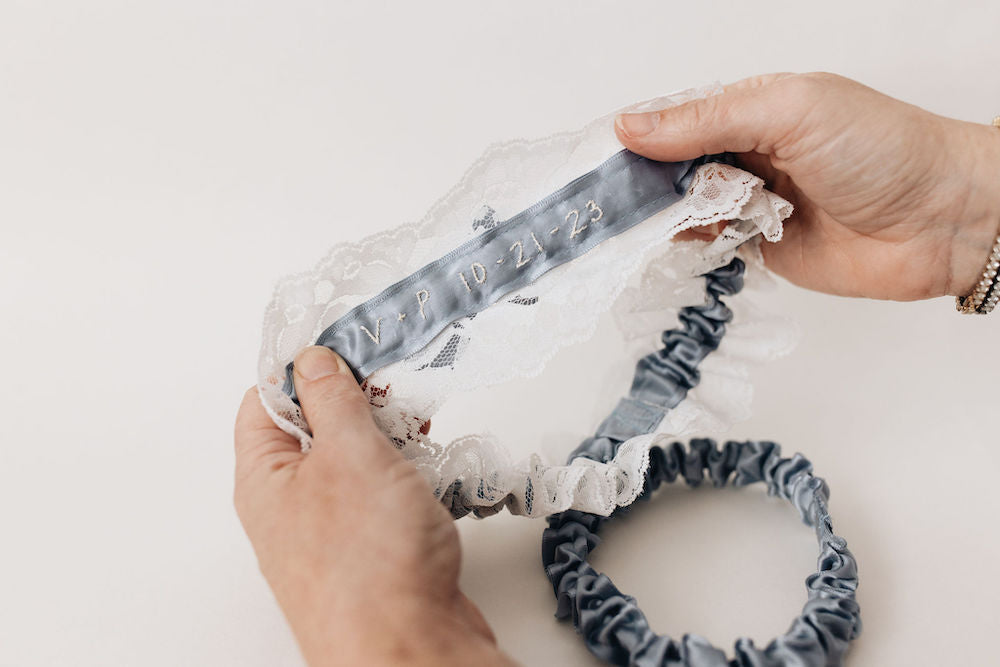 custom ivory embroidery on main garter of dusty blue satin wedding garter set handmade by The Garter Girl