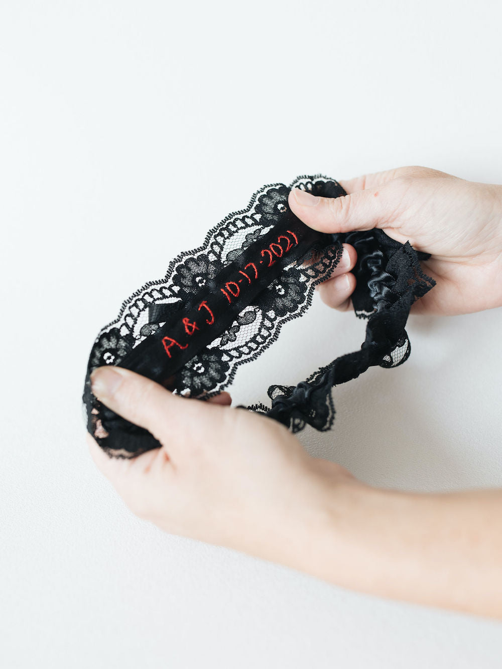 personalized wedding garter with black lace and velvet and custom red embroidery by heirloom designer, The Garter Girl