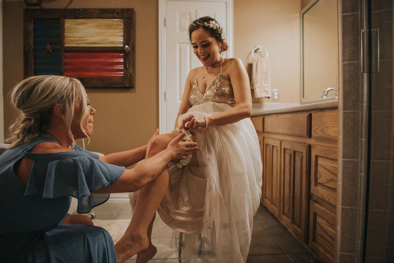 bride and bridesmaid putting on wedding garter