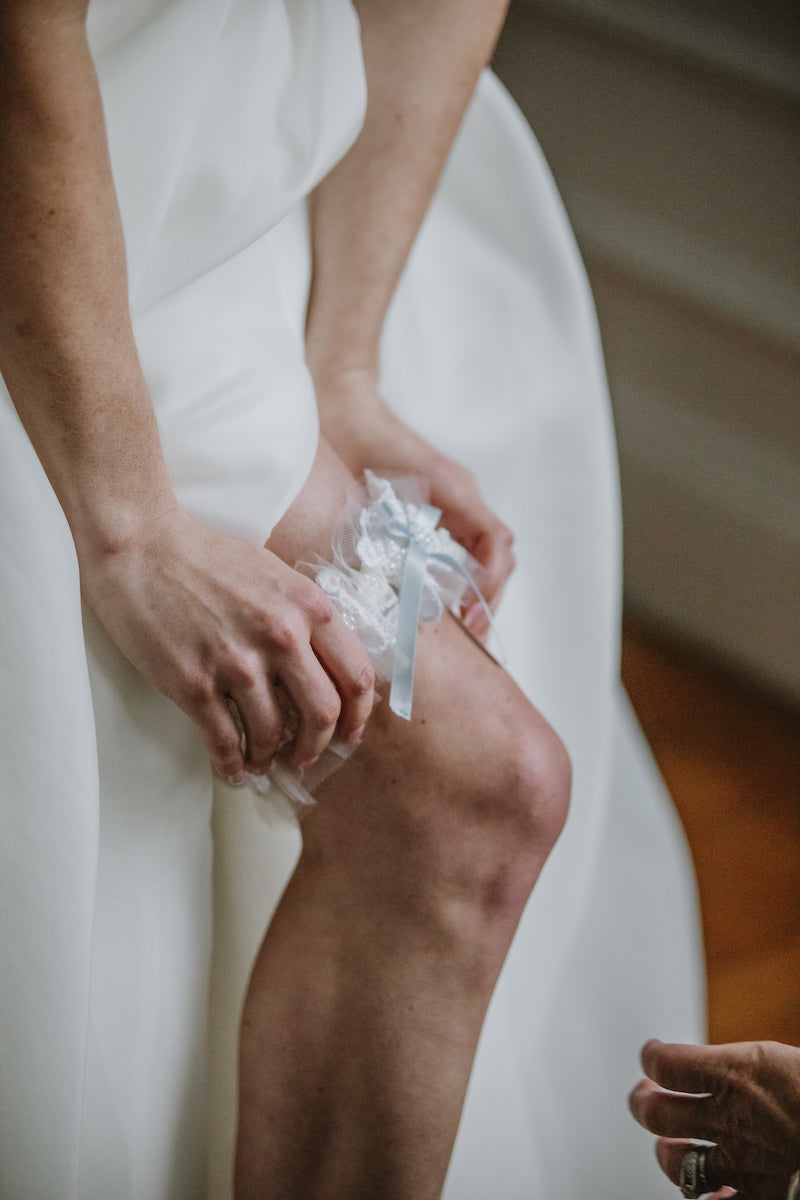 Bride Putting On Wedding Garter Made From Mom's Wedding Dress