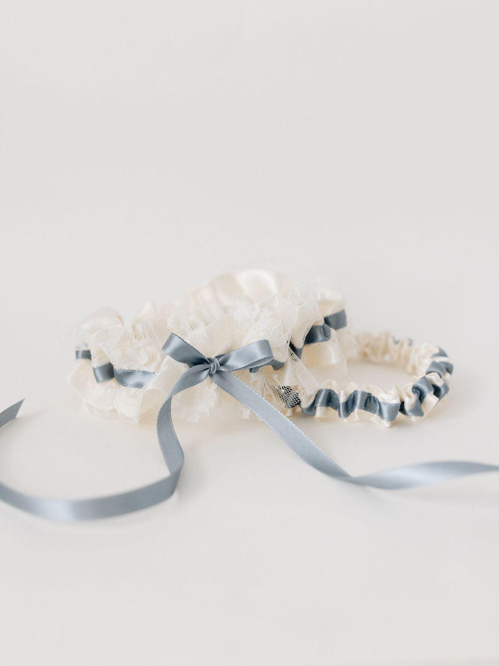 cream wedding garter set with dusty blue ribbon and embroidery handmade by wedding expert The Garter Girl