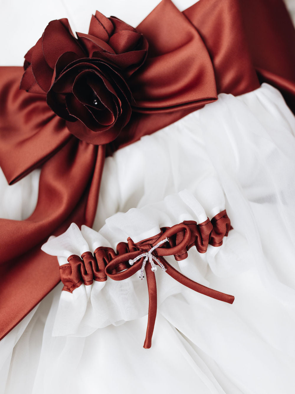 custom white main wedding garter with red detailing from bride's flower girl dress at mom's wedding handmade by The Garter Girl