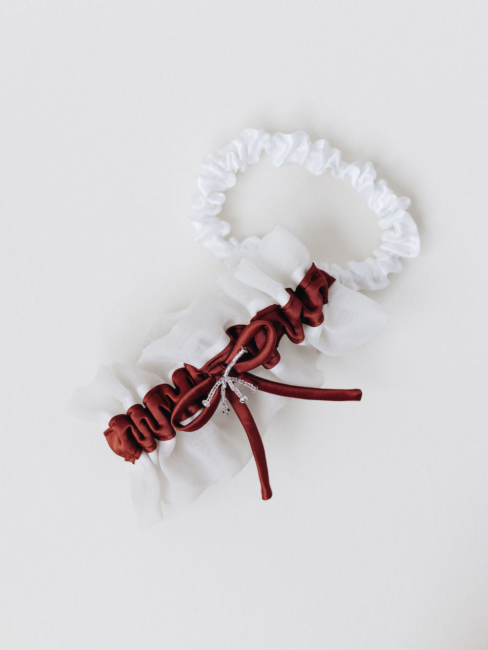 custom white wedding garter set with main and tossing garter and red detailing from bride's flower girl dress at mom's wedding handmade by The Garter Girl