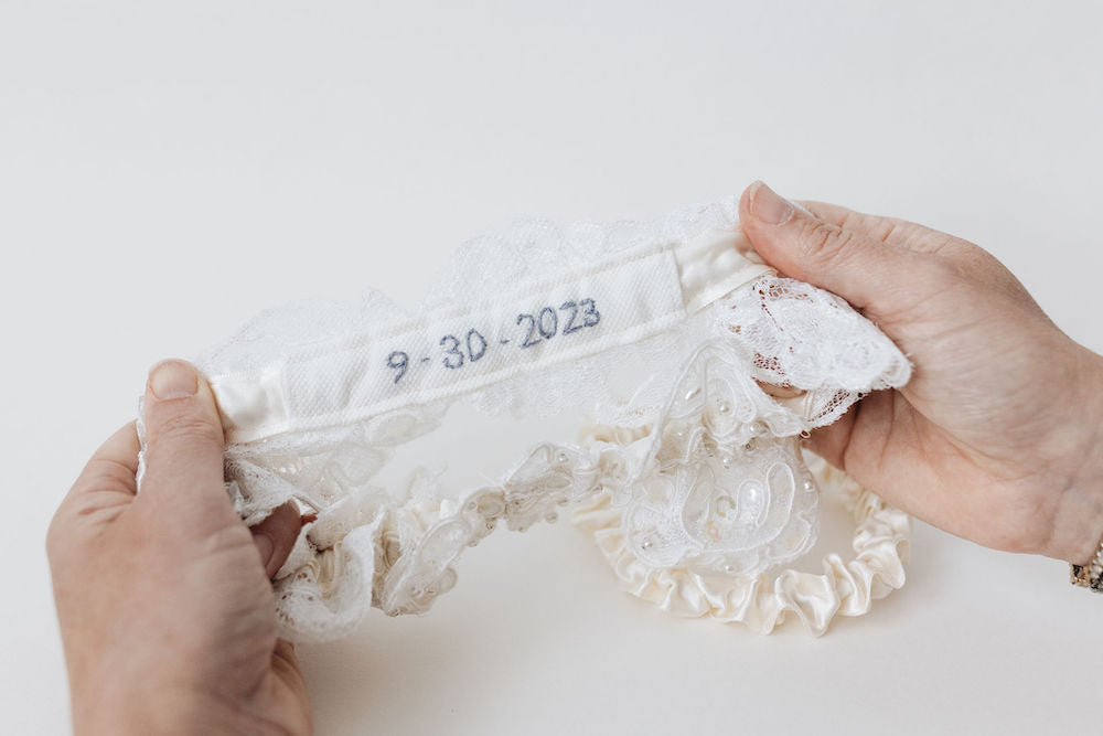 wedding heirloom garter with ivory lace main garter and custom blue embroidery from mom's wedding dress hem handmade by The Garter Girl