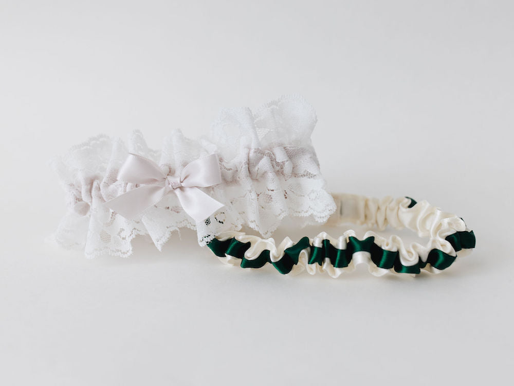 two personalized wedding garters with ivory satin and a green satin ribbon and ivory lace with a blush pink satin bow handmade by The Garter Girl