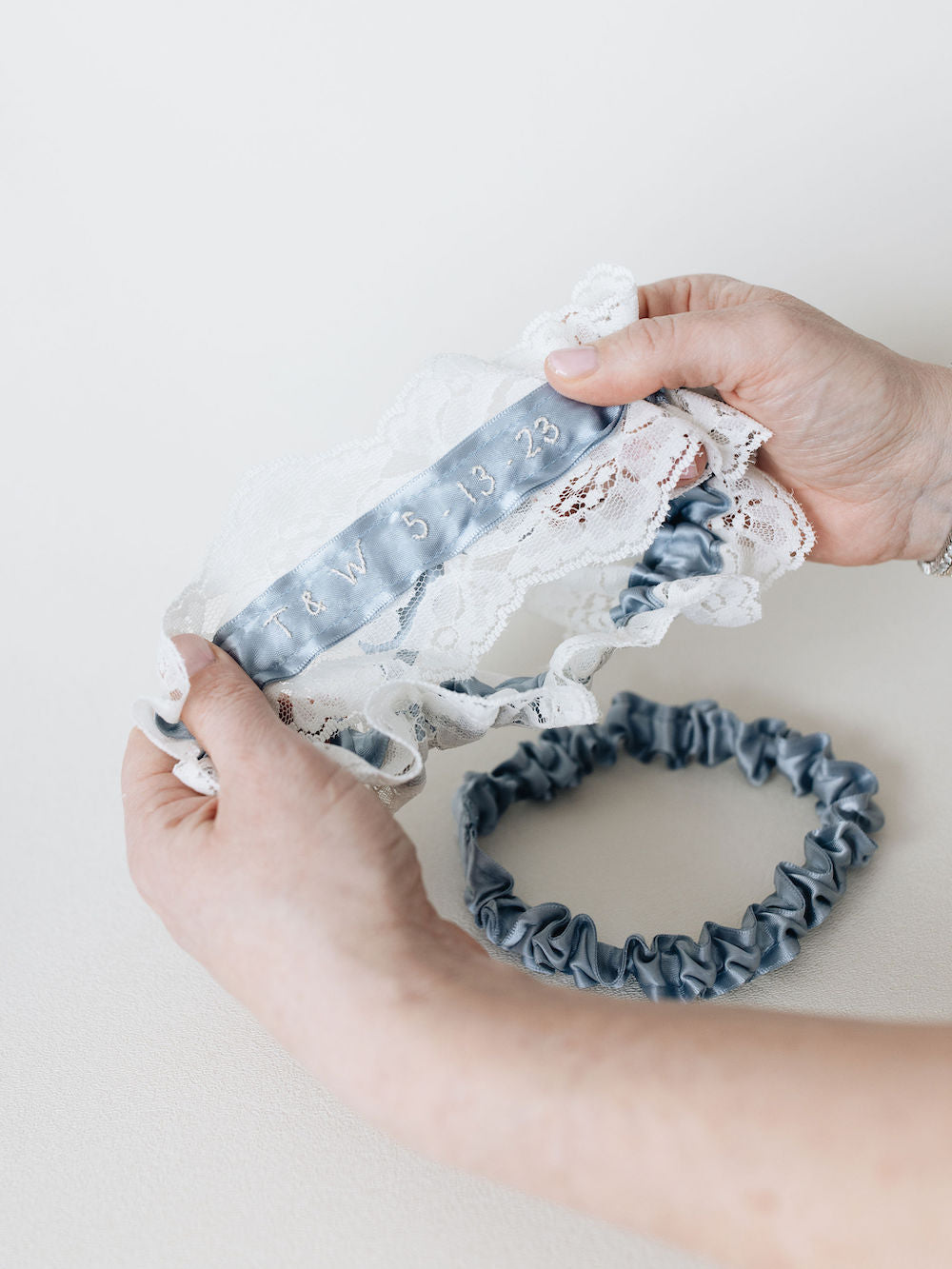 personalized embroidery on ivory lace main garter with blue satin tossing garter handmade by The Garter Girl