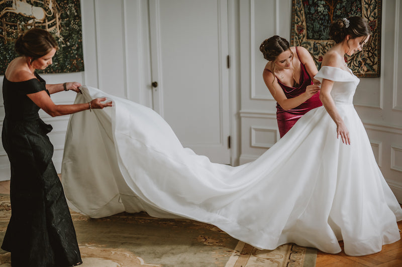 Sister and Mom Helping Bride in Wedding Dress