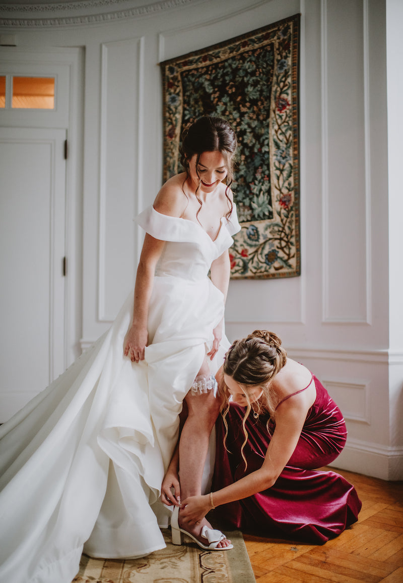 Sister Helping Bride Place Wedding Garter and Buckle Shoes