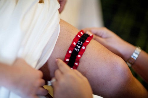 bride-putting-on-red-white-polka-dot-embroidered-garter