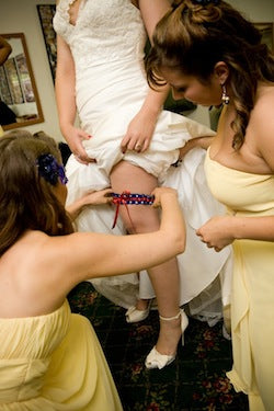 bridesmaids-helping-bride-with-wedding-garter-The-Garter-Girl-by-Julianne-Smith-Photo-credit-Tiffany-Atlas