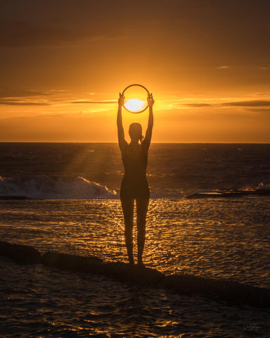 Melinda with Pilates ring at sunrise by the ocean