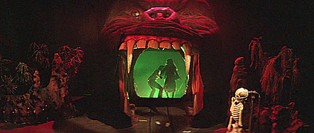 Two people entering a very spooky looking funhouse through a gorilla's mouth with green smoke.